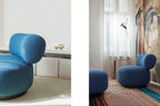 Sessel mit rundem Rücken und passendem Pouf vor asiatischer Wandkunst