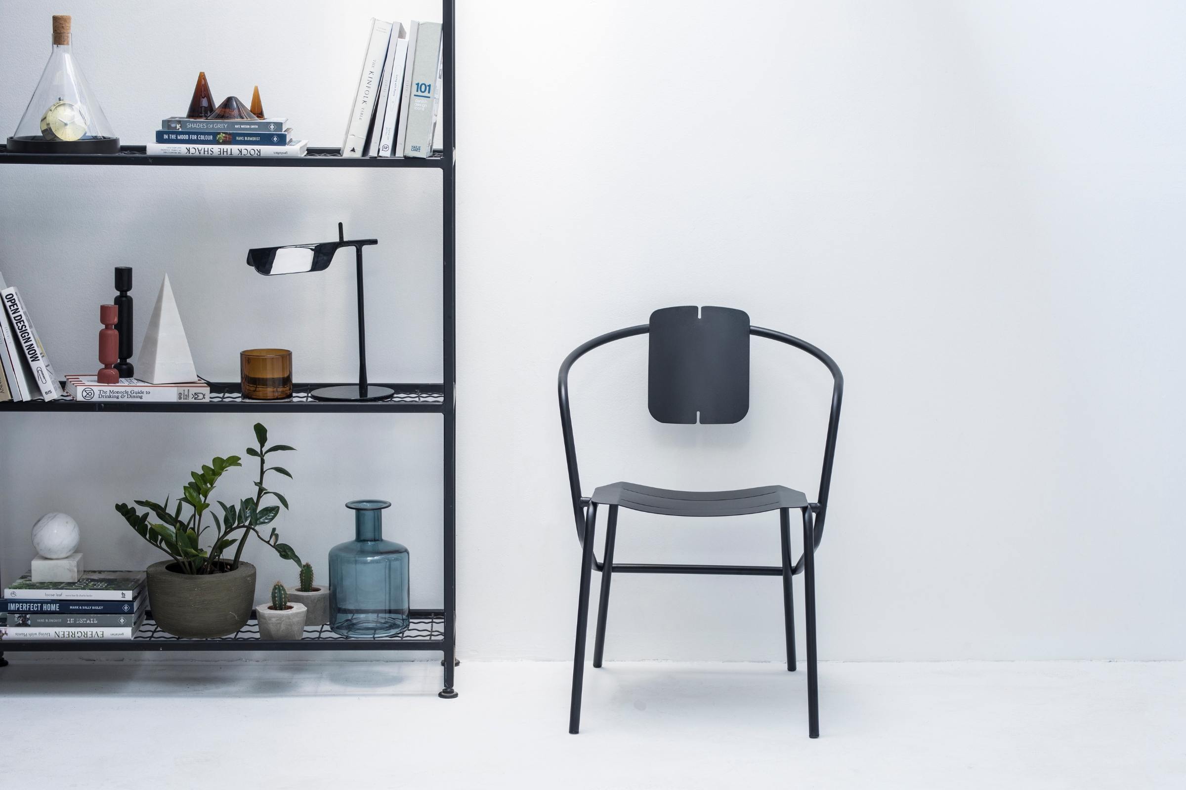 ATAMAN Designer Minimalisticher Gartenstuhl neben einem Regal mit Deko-Elementen
