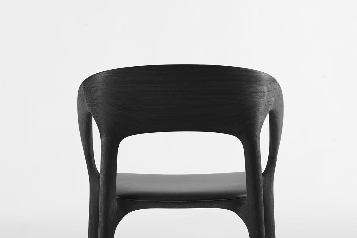 Minimalistischer Stuhl Sofi mit nahtlosen Holzübergängen und schwarzer Sitzfläche