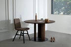 Innenaufnahme mit dem GROOVE Massivholz Esstisch rund, kombiniert mit einem modernen Stuhl und minimalistischer Dekoration in einem weißen Raum
