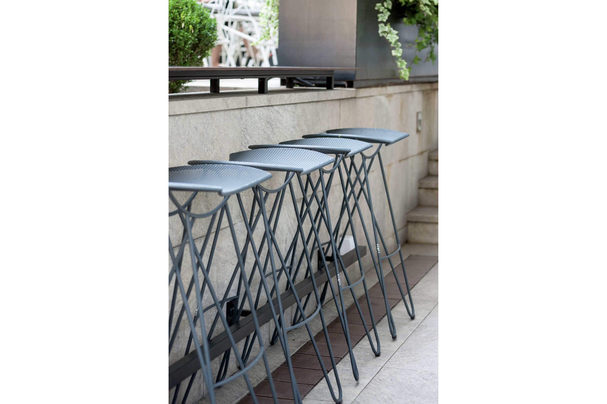 Mehrere Gartenbarhocker an einer Outdoor-Bar aufgereiht