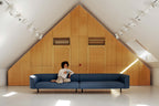 Extralanges blaues Sofa mit einer Person in einem minimalistischen Raum